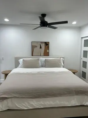 a bedroom with a large bed with a ceiling fan at La Jolla Townhouse steps away from Windansea beach in San Diego