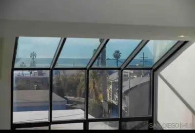 a window in a building with a view of the ocean at La Jolla Townhouse steps away from Windansea beach in San Diego