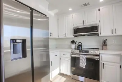 a kitchen with white cabinets and a stainless steel refrigerator at Rip Tide in San Diego