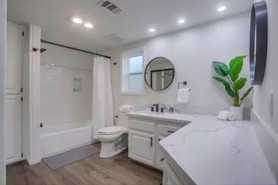 a white bathroom with a toilet and a sink and a mirror at Rip Tide in San Diego
