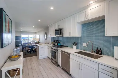 a kitchen with white cabinets and a dining room at Salt Life in San Diego