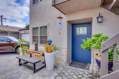 a blue door of a house with a bench and flowers at Costa Mesa Rental with Private Hot Tub and Fire Pit! in Costa Mesa
