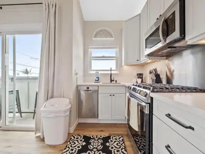 a kitchen with white cabinets and a stove top oven at A4609b- Sunset Cliffs Dream Apartment in San Diego