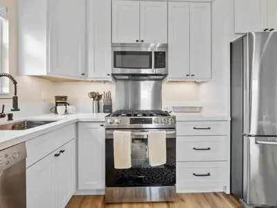 a kitchen with white cabinets and a stove with a microwave at A4609b- Sunset Cliffs Dream Apartment in San Diego