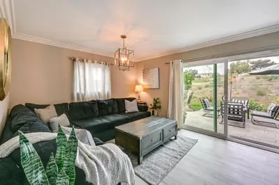 a living room with a green couch and a sliding glass door at San Diego Family Home with Lush Backyard Patio! in San Diego