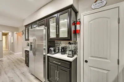 a kitchen with black cabinets and a stainless steel refrigerator at San Diego Family Home with Lush Backyard Patio! in San Diego