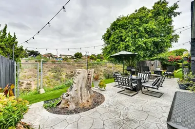 a patio with two benches and a tree stump at San Diego Family Home with Lush Backyard Patio! in San Diego
