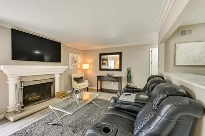 a living room with a black leather couch and a fireplace at San Diego Family Home with Lush Backyard Patio! in San Diego