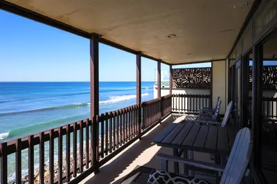 a balcony with a table and chairs and the ocean at Beachfront Retreat in Oceanside