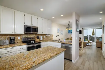a kitchen with white cabinets and granite counter tops at Oceanside Beach Condos in Oceanside