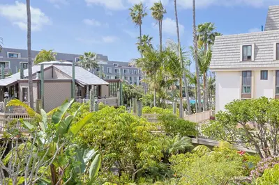 a garden with palm trees and a building at Oceanside Beach Condos in Oceanside