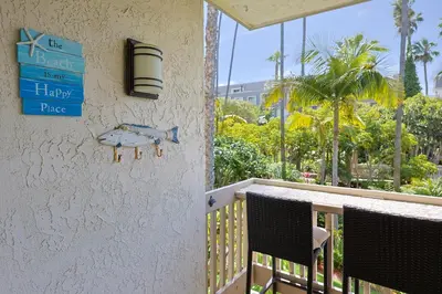 a sign on the side of a porch with two chairs at Oceanside Beach Condos in Oceanside