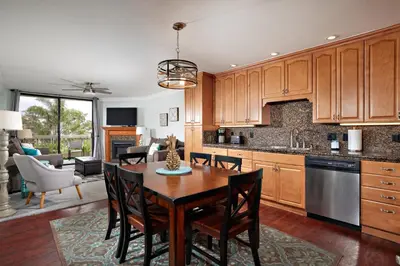 a kitchen with wooden cabinets and a table and chairs at Oceanside Beach Condos in Oceanside