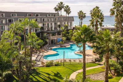 an aerial view of a resort with a pool and palm trees at Oceanside Beach Condos in Oceanside
