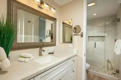 a white bathroom with a sink and a shower at Oceanside Beach Condos in Oceanside