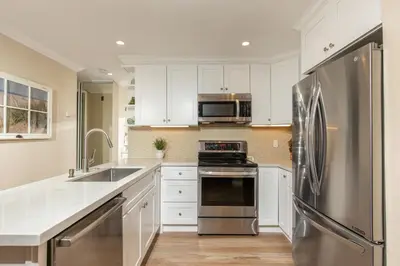 a kitchen with white cabinets and a stainless steel refrigerator at Oceanside Beach Condos in Oceanside