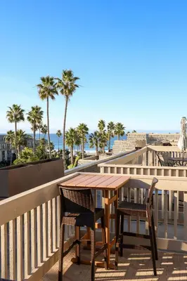 a table and chairs on a balcony with palm trees at Oceanside Beach Condos in Oceanside