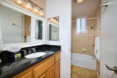 a bathroom with a sink and a mirror and a tub at Oceanside Beach Condos in Oceanside
