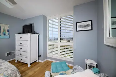 a bedroom with a bed and a dresser and a window at Oceanside Beach Condos in Oceanside
