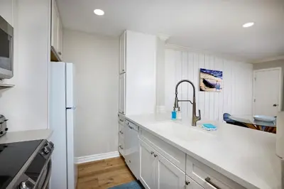 a white kitchen with a sink and a refrigerator at Oceanside Beach Condos in Oceanside