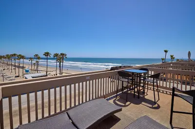a balcony with a table and chairs and the beach at Oceanside Beach Condos in Oceanside