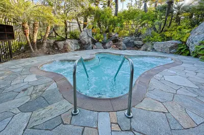a hot tub in a backyard with a stone patio at Oceanside Beach Condos in Oceanside