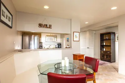 a dining room with a glass table and red chairs at Oceanside Beach Condos in Oceanside