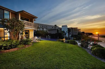 a lawn in front of a building at sunset at Oceanside Beach Condos in Oceanside