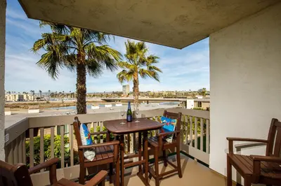 a balcony with a table and chairs and palm trees at Oceanside Beach Condos in Oceanside