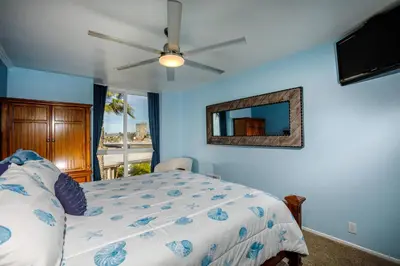 a bedroom with a bed with a ceiling fan and a mirror at Oceanside Beach Condos in Oceanside