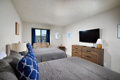 a bedroom with two beds and a flat screen tv at Oceanside Beach Condos in Oceanside