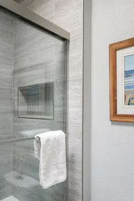 a bathroom with a glass shower with a towel at Oceanside Beach Condos in Oceanside