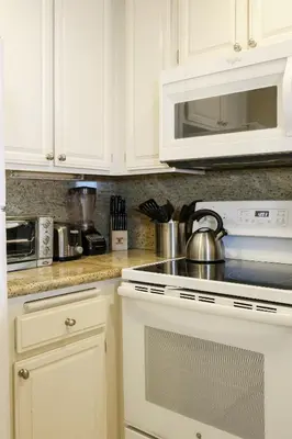 a kitchen with white cabinets and a stove and microwave at Oceanside Beach Condos in Oceanside