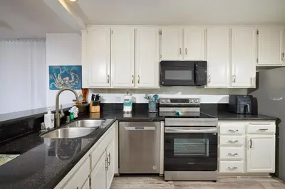 a kitchen with white cabinets and stainless steel appliances at Oceanside Beach Condos in Oceanside
