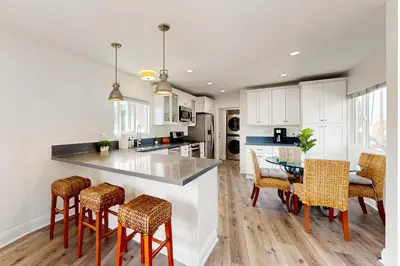a kitchen with white cabinets and a table and chairs at The Cliffside Bungalow in San Diego