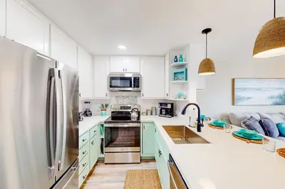 a kitchen with white cabinets and a stainless steel refrigerator at Pacific Street Hideaway in Oceanside