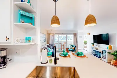 a kitchen with a sink and a living room at Pacific Street Hideaway in Oceanside