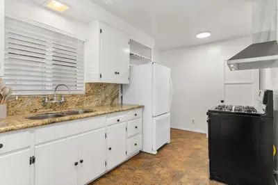a kitchen with white cabinets and a black refrigerator at Cozy, home with hottub and patio in San Diego