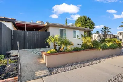 a home with a fence and palm trees at Cozy, home with hottub and patio in San Diego