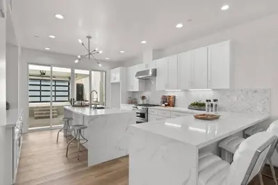 a kitchen with white cabinets and a large white island at Modern, Spacious, home w rooftop view in San Diego