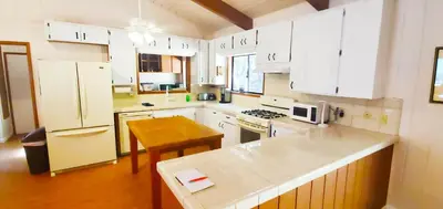 a kitchen with white cabinets and a table in it at The Bungalow Partial Home Rental in Julian