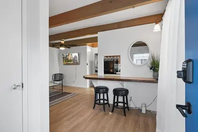 a kitchen and living room with a counter and stools at Mission Bay Condo - Steps to Sand, Dining, AC, Parking & Shops! in San Diego