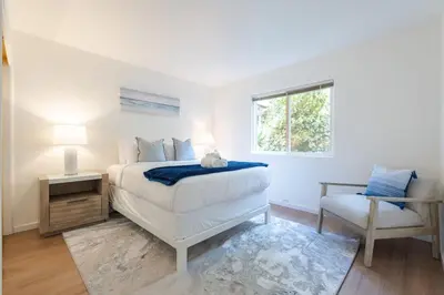 a white bedroom with a bed and a chair at Sunset Serenity On The Cliffs - Balcony- Oceanview in San Diego