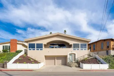 a house with two palm trees on top of it at Sunset Serenity On The Cliffs - Balcony- Oceanview in San Diego