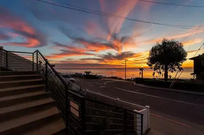 a sunset over a street with a fence and stairs at Sunset Serenity On The Cliffs - Balcony- Oceanview in San Diego