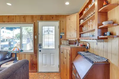 a kitchen with wooden walls and a door and a couch at Downtown Carlsbad Apartment Less Than half Mi to Beach! in Carlsbad