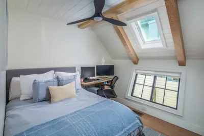 a bedroom with a bed with a ceiling fan and a desk at Neptune Ocean View Masterpiece in Encinitas