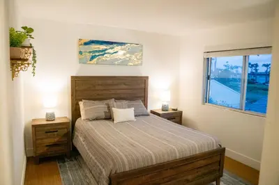 a bedroom with a bed with two night stands and a window at 1 Block from Beach - Steps from Restaurants & Shops in Oceanside