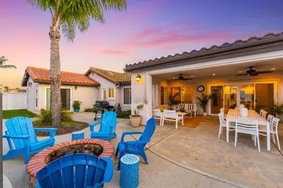 a patio with blue chairs and tables and a palm tree at Villa Descanso in Oceanside