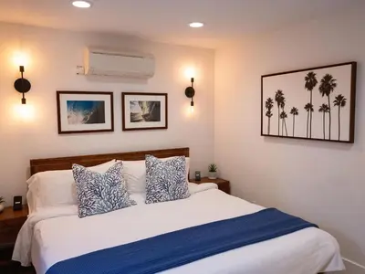 a bedroom with a bed with blue and white pillows at Luxury 2BR Steps to Beach & Pier with AC plus Garage Parking in Newport Beach